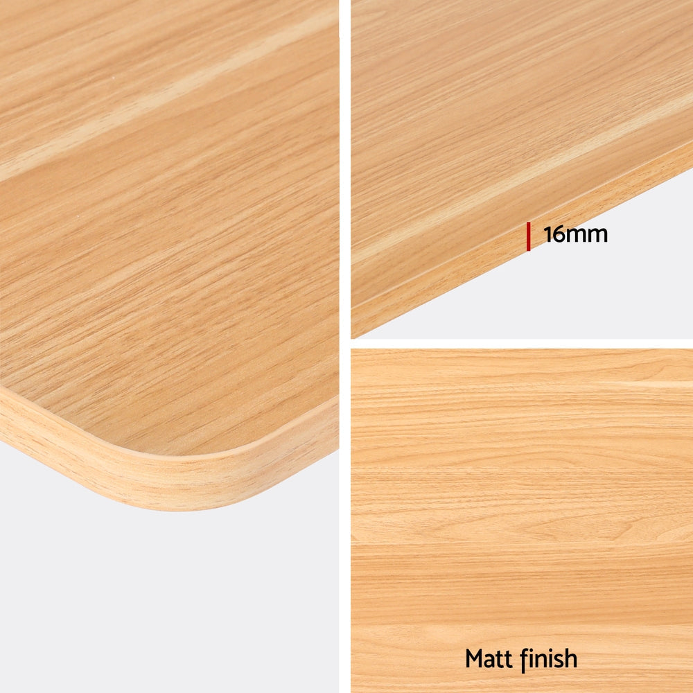 Electric sit stand desk with a natural wood top raised to standing height