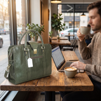 The Envoy Leather Briefcase, Olive Green — on a cafe table
