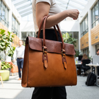 The Signature Leather Laptop Bag, Tan Flap 17 inch — carried in an office atrium