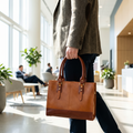 The Signature Leather Laptop Bag, Tan 15 inch — carried in an office lobby