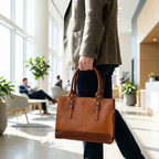 The Signature Leather Laptop Bag, Tan 15 inch — carried in an office lobby