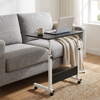 Black height adjustable mobile desk beside a sofa with a laptop