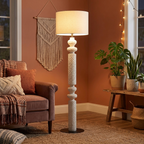Gold-tone floor lamp with linen shade in a living room corner in the evening