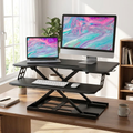 Black sit-stand desk riser raised on a desk with a monitor and laptop