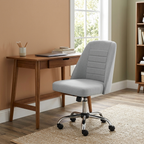 Armless tufted desk chair on wheels at a small desk in a home office corner
